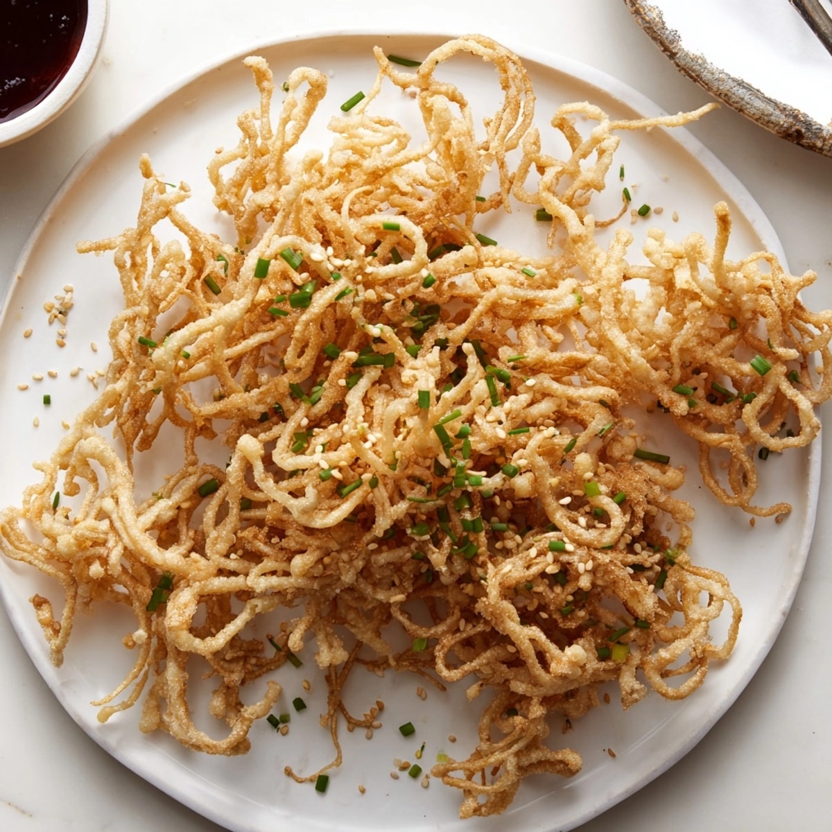 Golden, crispy enoki mushrooms, a tantalizing snack shown served hot with scallions.