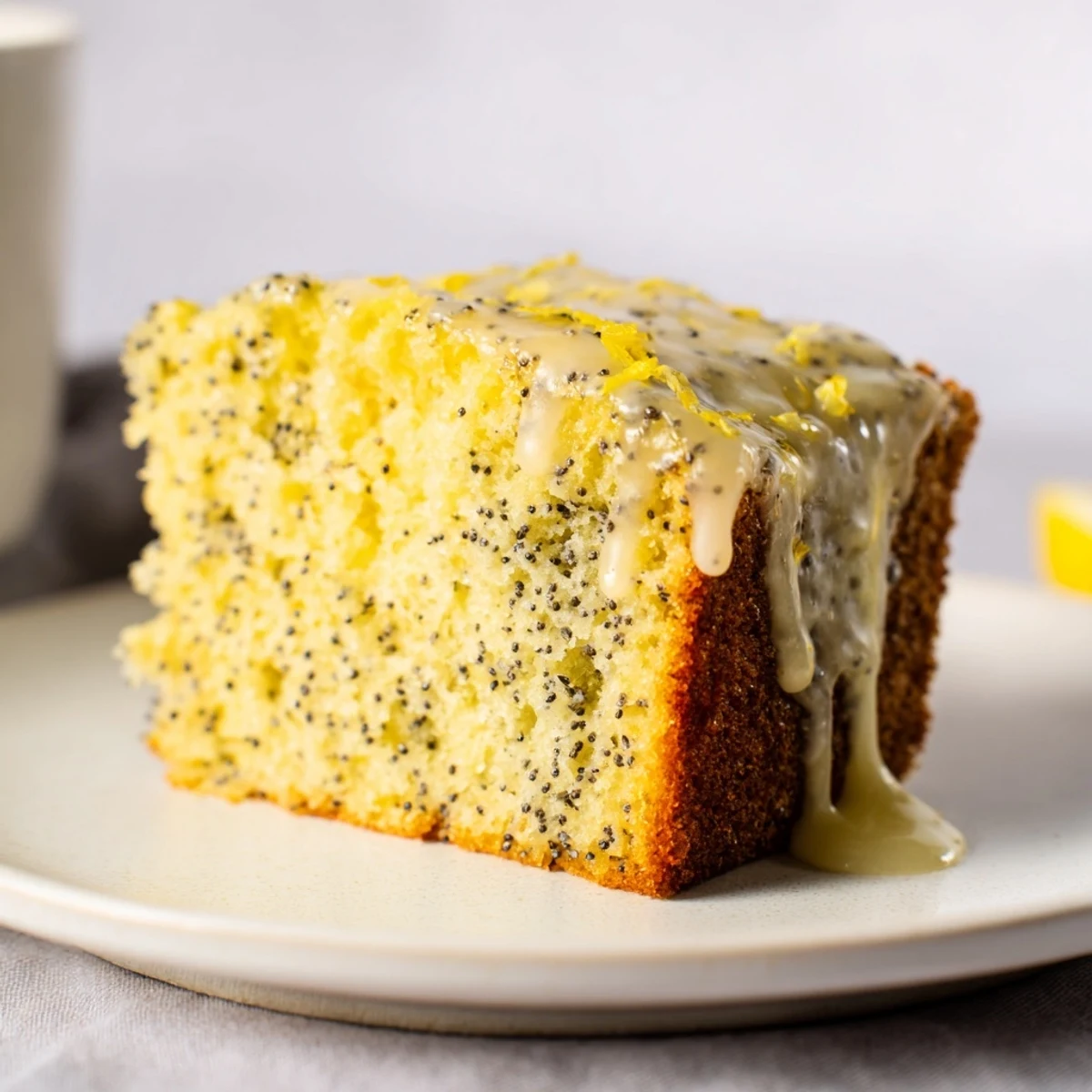 Close-up of moist Lemon Poppy Seed Cake with a drizzle of sweet and zesty lemon icing.