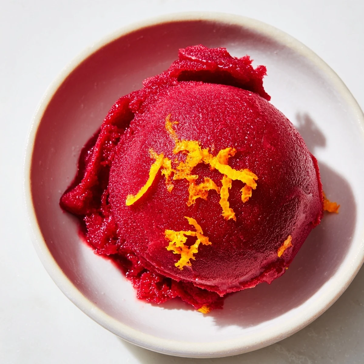 A scoop of homemade Cranberry Sorbet, boasting a deep red hue and delightful texture in a serving bowl.