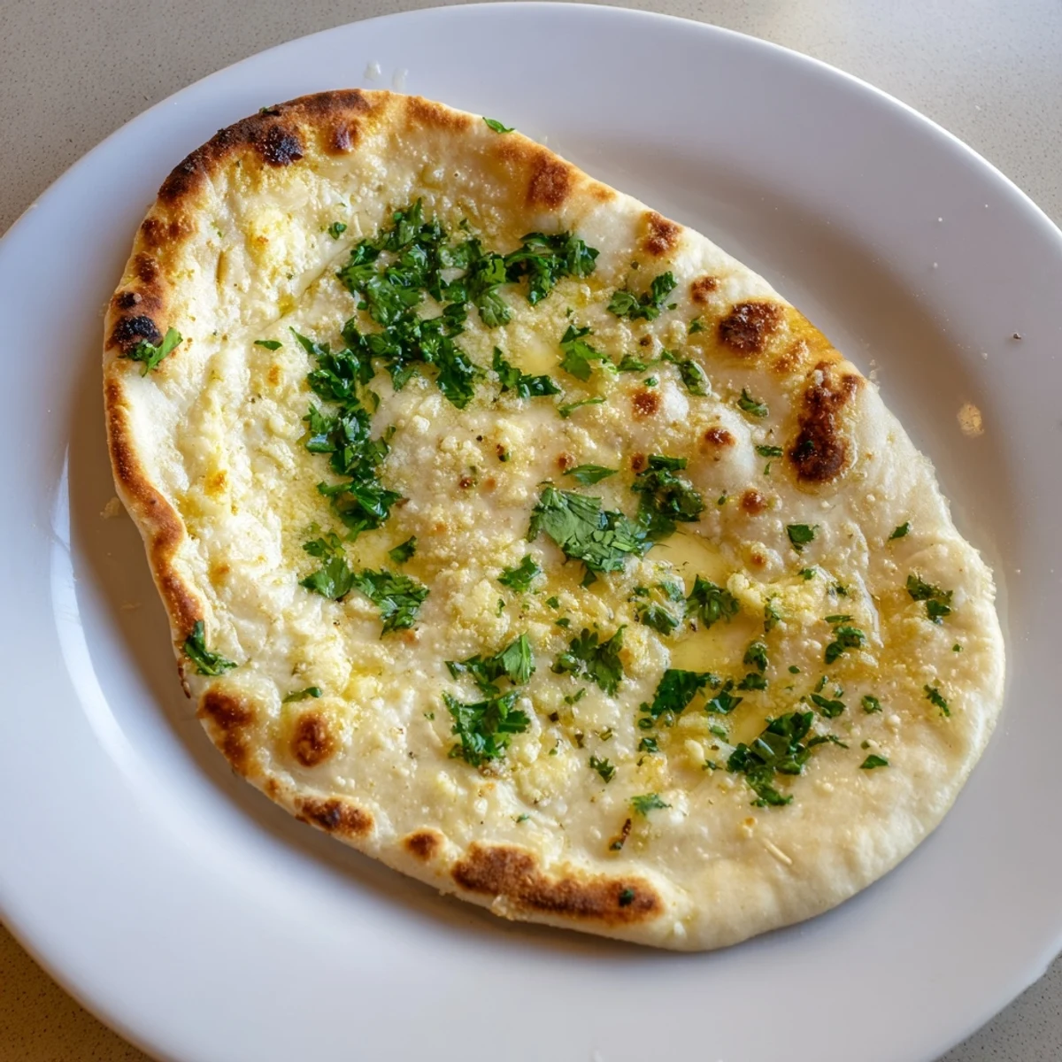 Freshly baked Garlic Naan Bread, showing soft, pillowy texture and aromatic garlic topping.