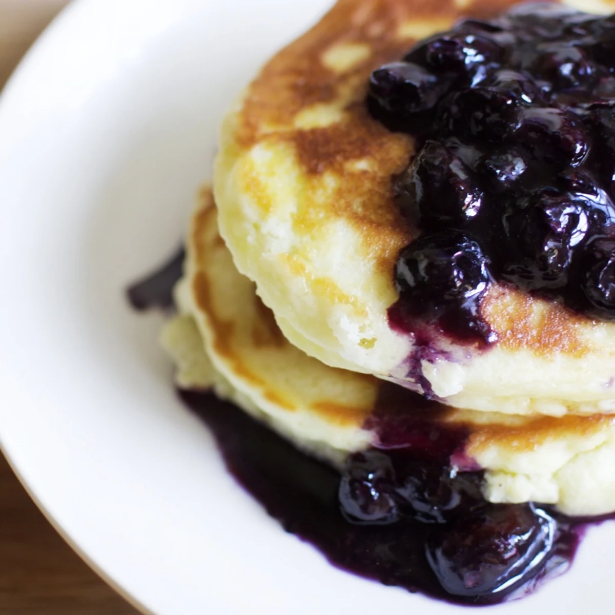 Fluffy Lemon Ricotta Pancakes drizzled with vibrant blueberry syrup, ready for a delicious brunch.