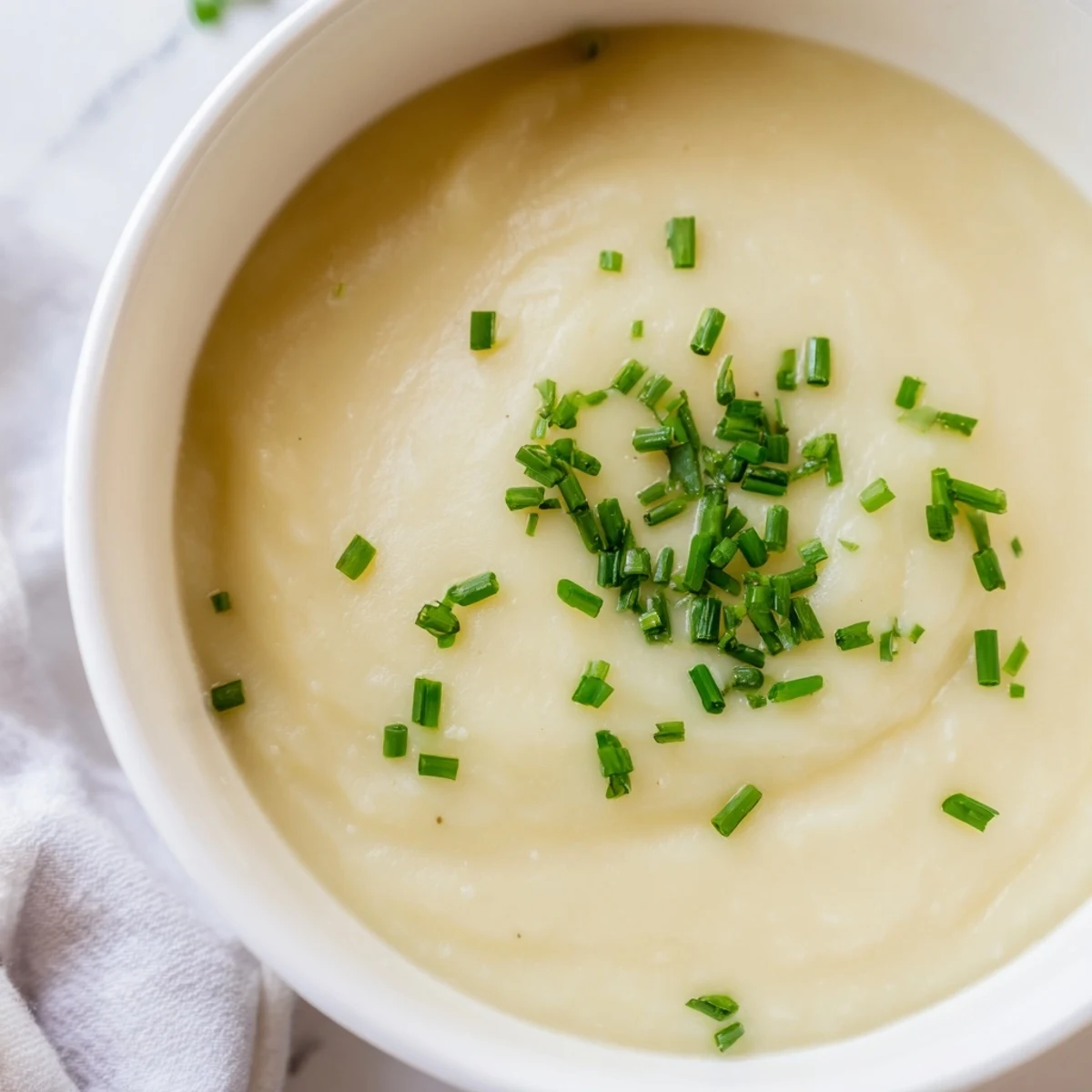 Rustic pot of Creamy Potato Leek Soup with Chives, featuring velvety texture and vibrant green garnish ready to serve.