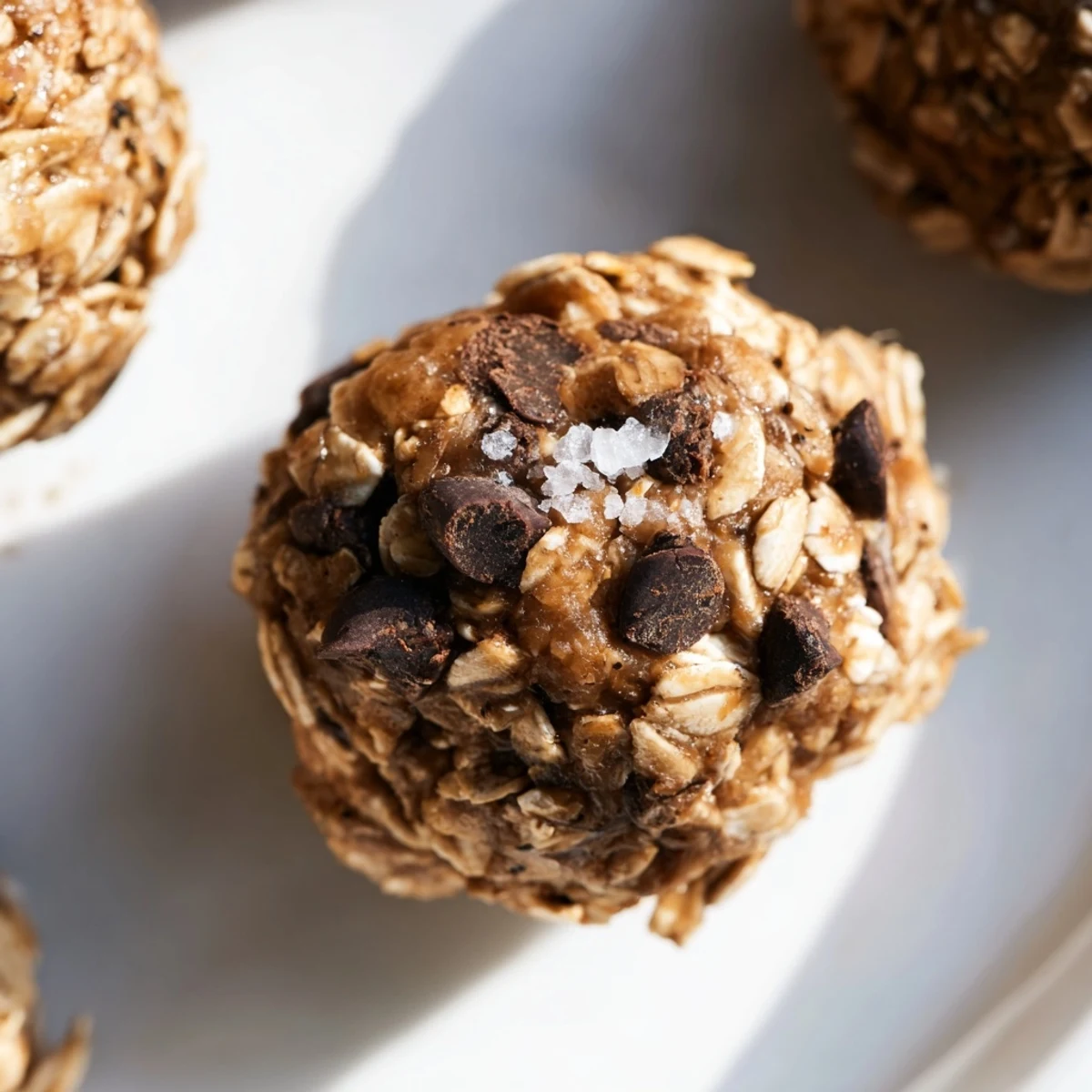 Close-up shot of Chocolate Peanut Butter Energy Balls on a marble surface, revealing their rolled oats and flaxseed texture.