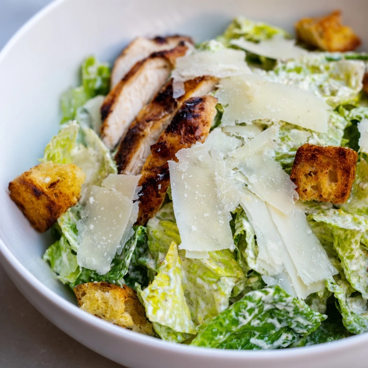 Classic Caesar Salad with Grilled Chicken is served on a plate with creamy dressing and crunchy croutons.