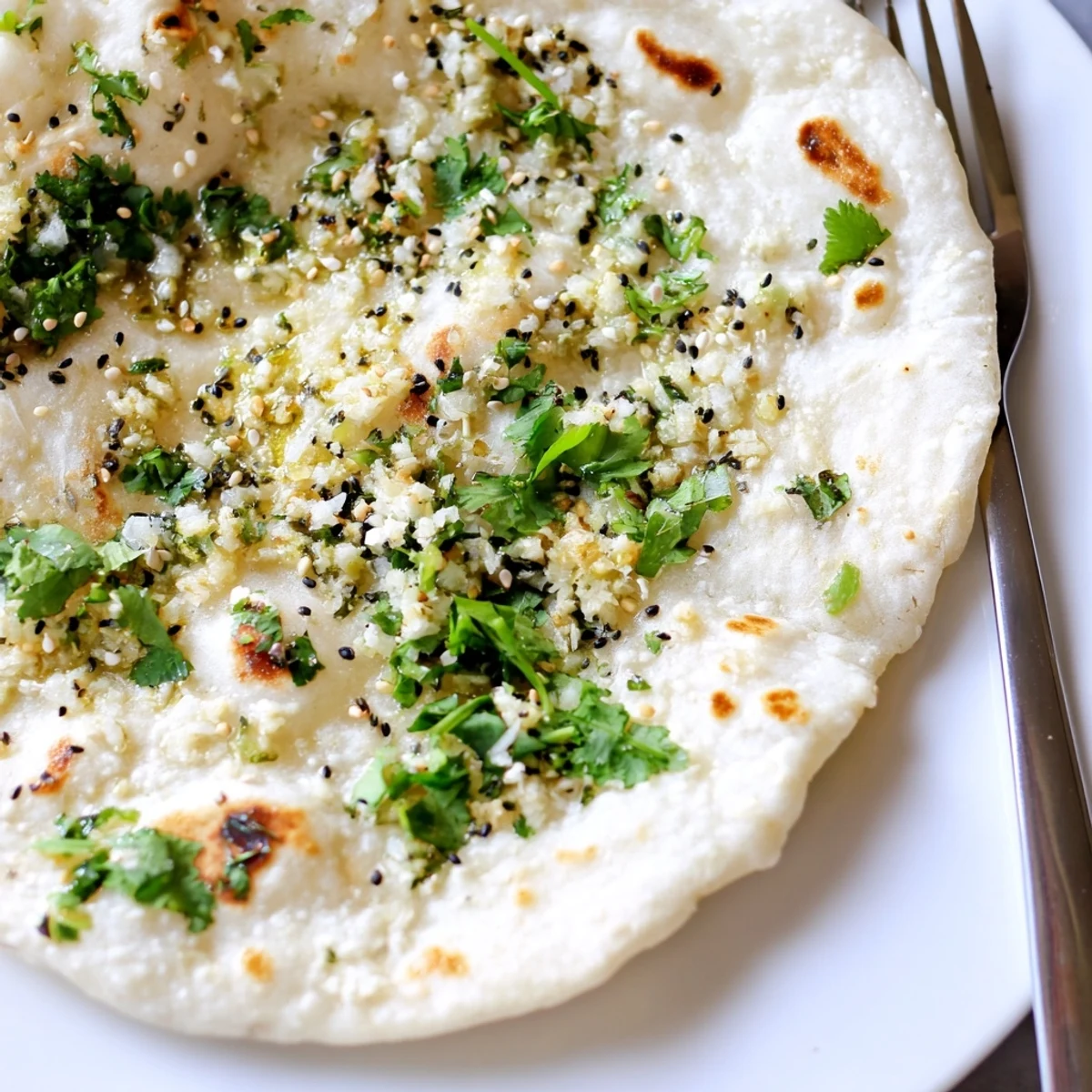 Golden-brown Garlic Naan Bread with Nigella Seeds, brushed with ghee and fresh herbs, ready to serve with a rich curry.