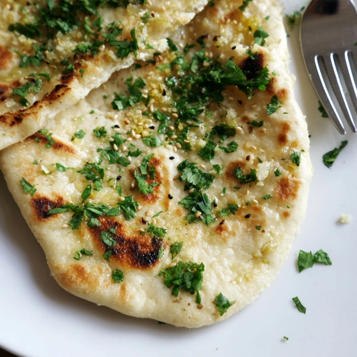 Fluffy and soft Garlic Naan Bread with Nigella Seeds cooling on a wire rack, garnished with chopped cilantro for a vibrant presentation.