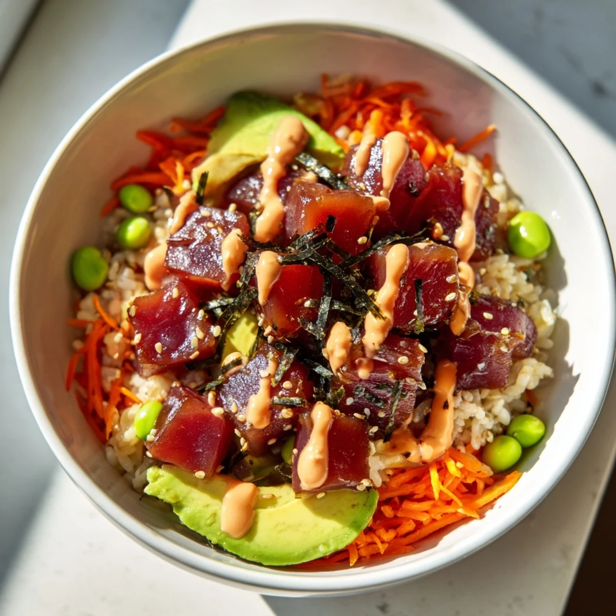 This photo shows a vibrant Spicy Tuna Poke Bowl with Sriracha Mayo, featuring diced tuna, creamy avocado, and crunchy cucumber atop fluffy rice.