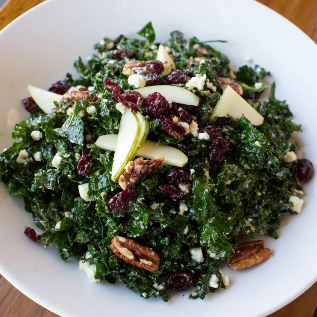 A vibrant bowl of Winter Kale Salad with Dried Cranberries, featuring chopped kale, sliced apples, and toasted pecans tossed in a zesty citrus dressing.