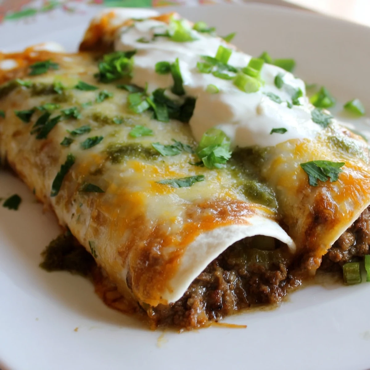 Gooey Beef Enchiladas with Green Sauce bubbling with melted Monterey Jack cheese and a creamy tangy sauce.