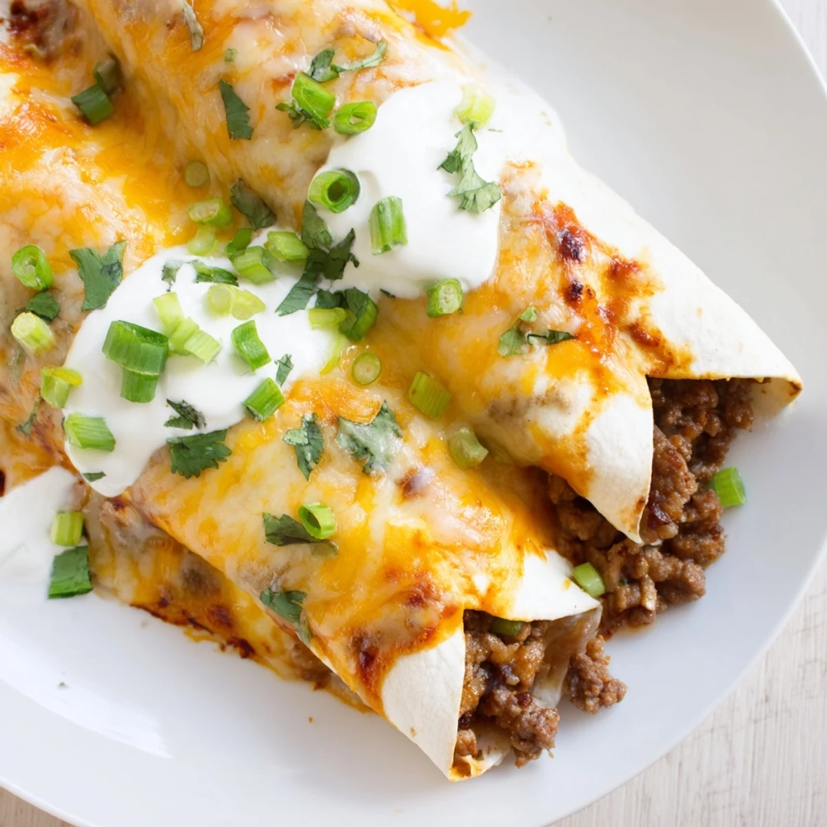 Spicy ground beef filling wrapped in soft flour tortillas, smothered in vibrant green sauce and fresh cilantro.