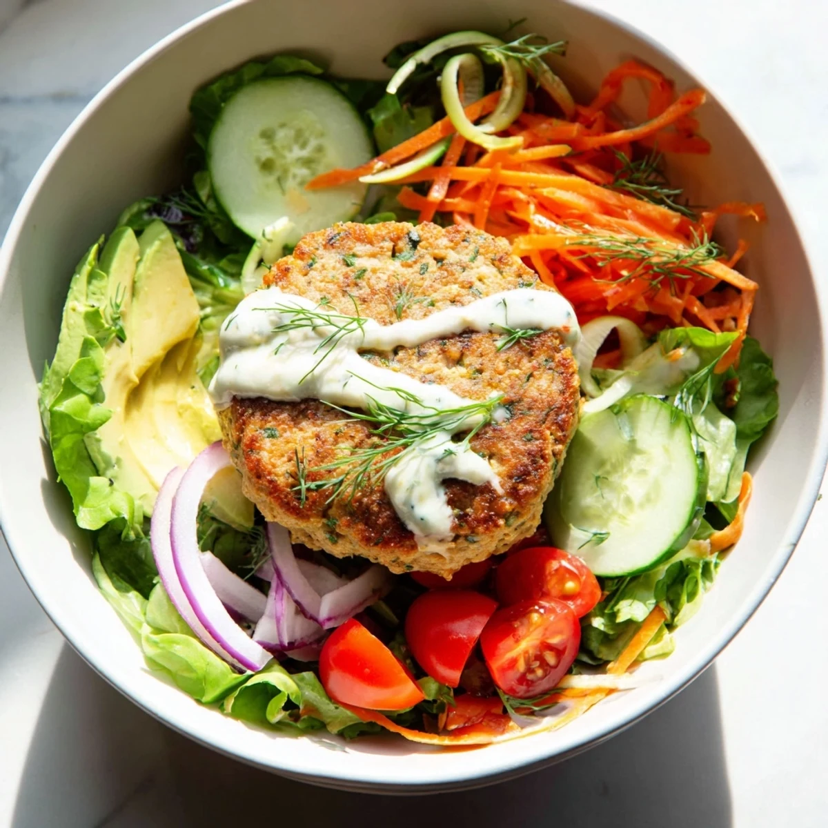 Savory turkey burger salad bowl with juicy grilled patties, crisp mixed greens, avocado, and creamy dill yogurt dressing on a white plate.  