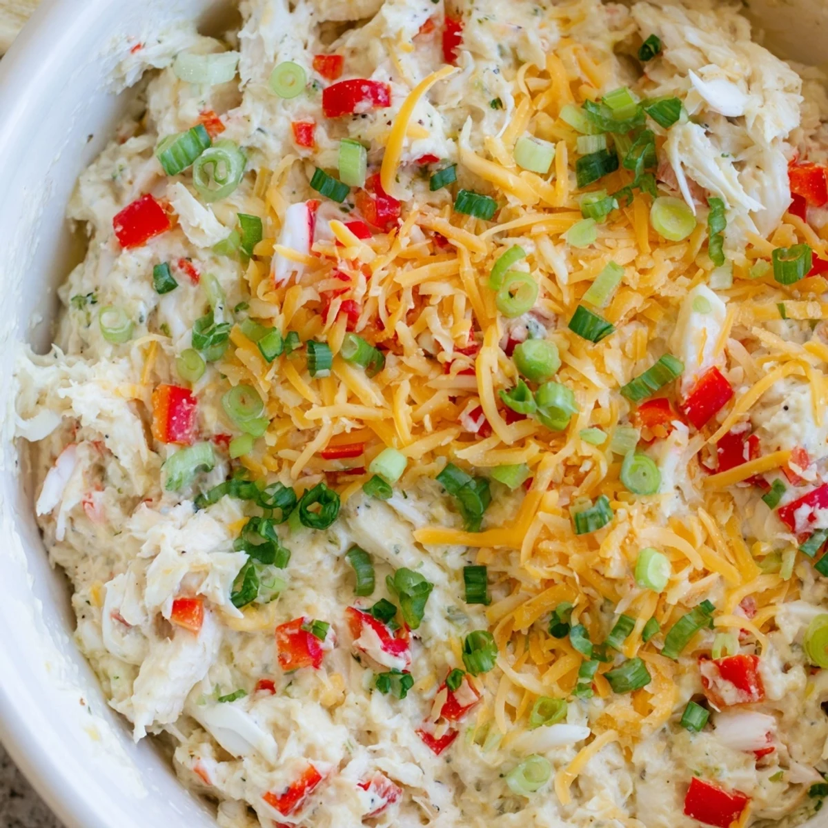 Fresh, bubbly Mardi Gras Crab Dip baked in a dish, garnished with parsley and green onions, served warm with crispy baguette slices and colorful bell peppers.