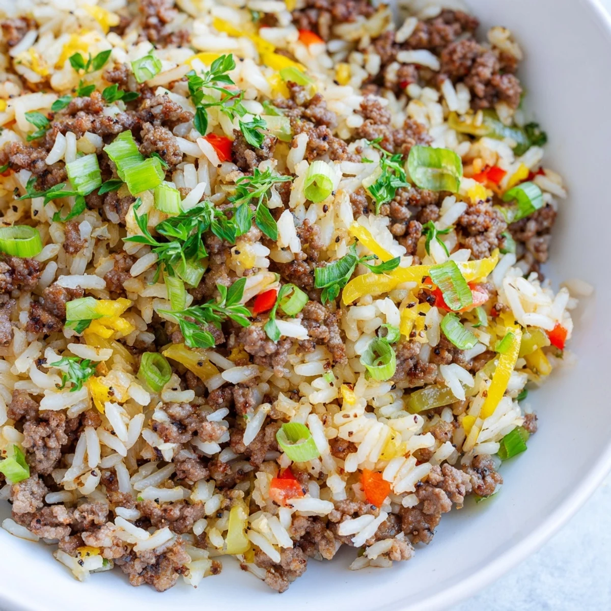 A steaming skillet of Cajun Dirty Rice with Ground Beef and Peppers, garnished with fresh parsley and sliced green onions.