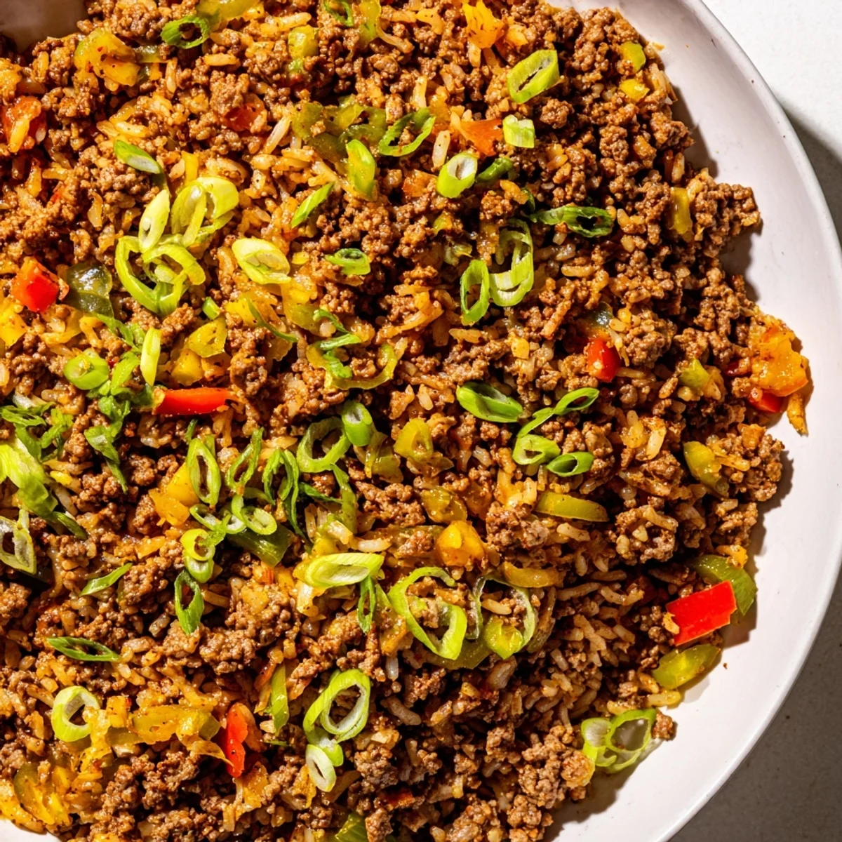 Steaming bowl of Cajun Dirty Rice with Ground Beef and Peppers, garnished with fresh parsley.  