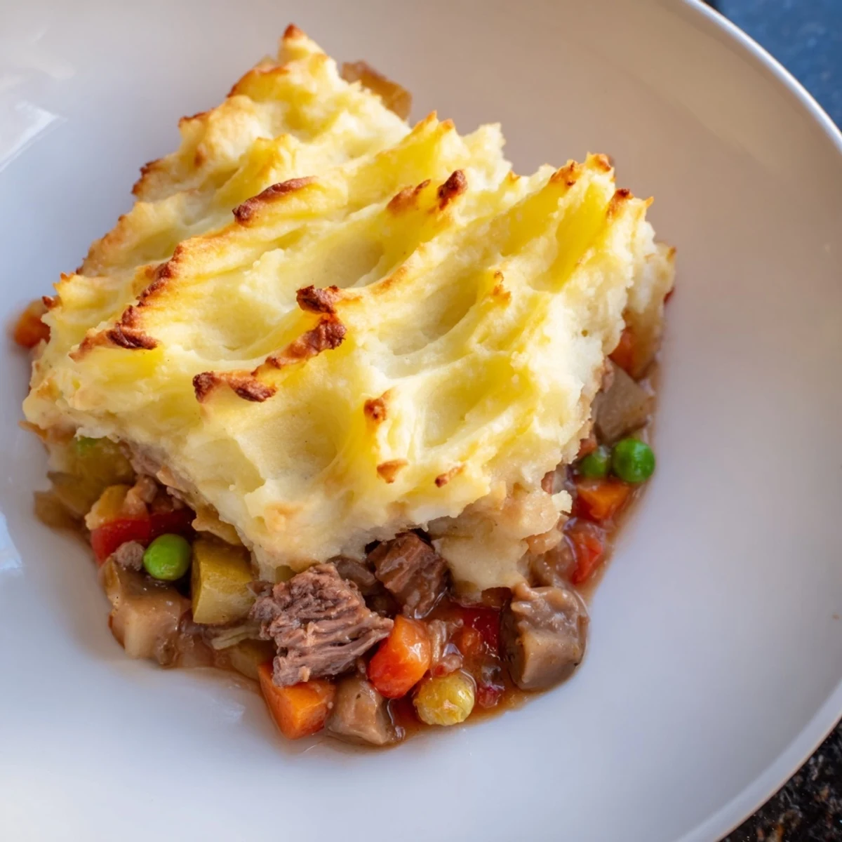 Rustic Shepherd's Pie with Braised Lamb and Vegetables in a baking dish, topped with fork-marked mashed potatoes.