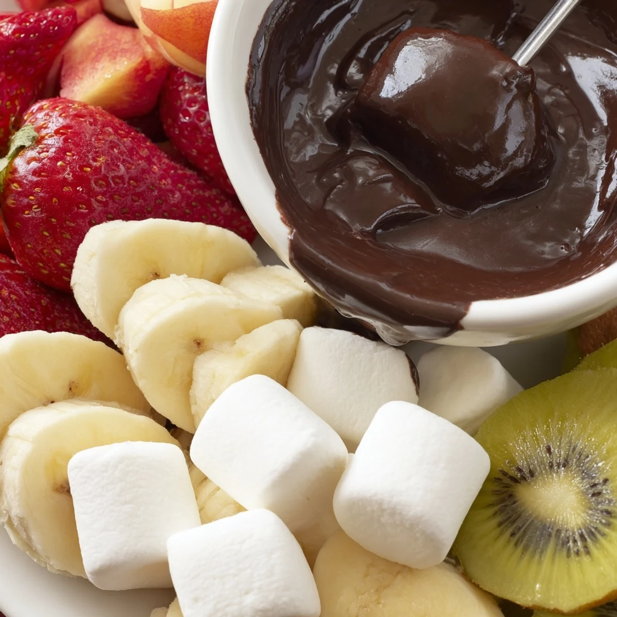 Silky, melted Romantic Chocolate Fondue with Marshmallows and Fruit waits for dipping strawberries and banana slices.