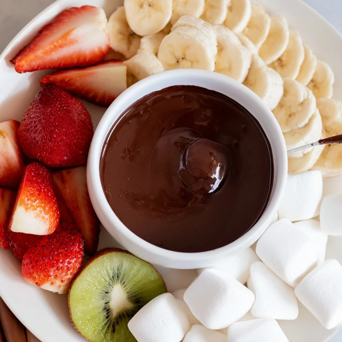 A decadent Romantic Chocolate Fondue with Marshmallows and Fruit served warm with fresh fruit and dessert skewers.