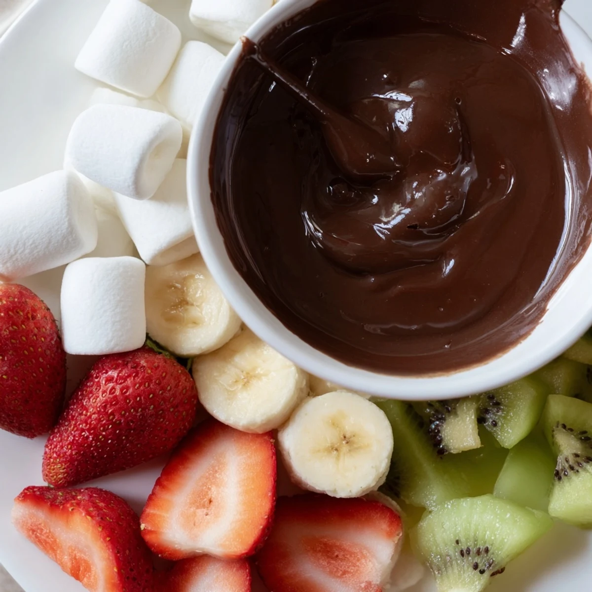 Close-up of Romantic Chocolate Fondue with Marshmallows and Fruit drizzled over juicy strawberries and apple wedges.