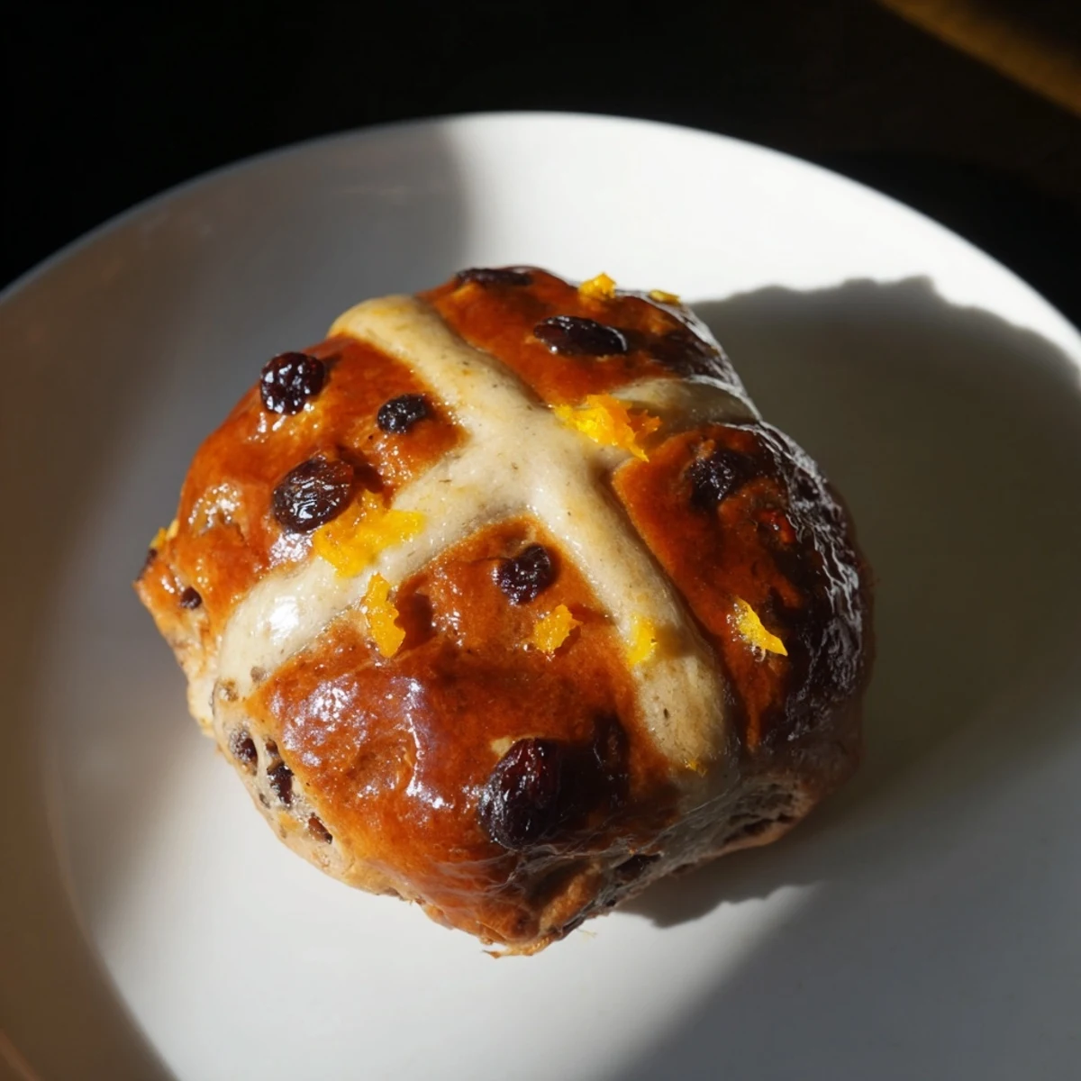 A close-up of Hot Cross Buns shows soft, fragrant crumb studded with currants, ready to be enjoyed with butter and a cup of coffee.