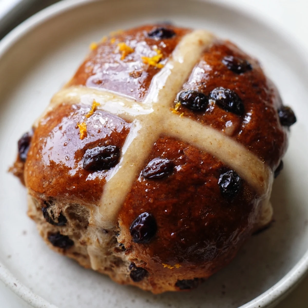 Golden brown Hot Cross Buns emerge from the oven, their spiced aroma filling the kitchen and their glossy glaze catching the warm morning light.
