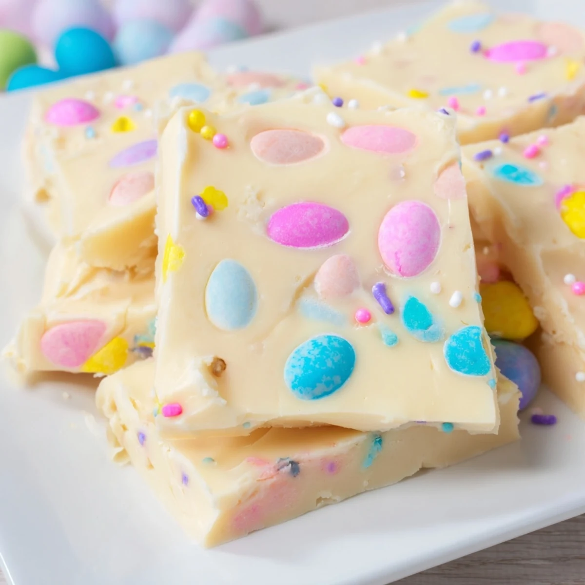 Easter Fudge squares stacked on a parchment-lined board, showcasing creamy texture and spring colors.