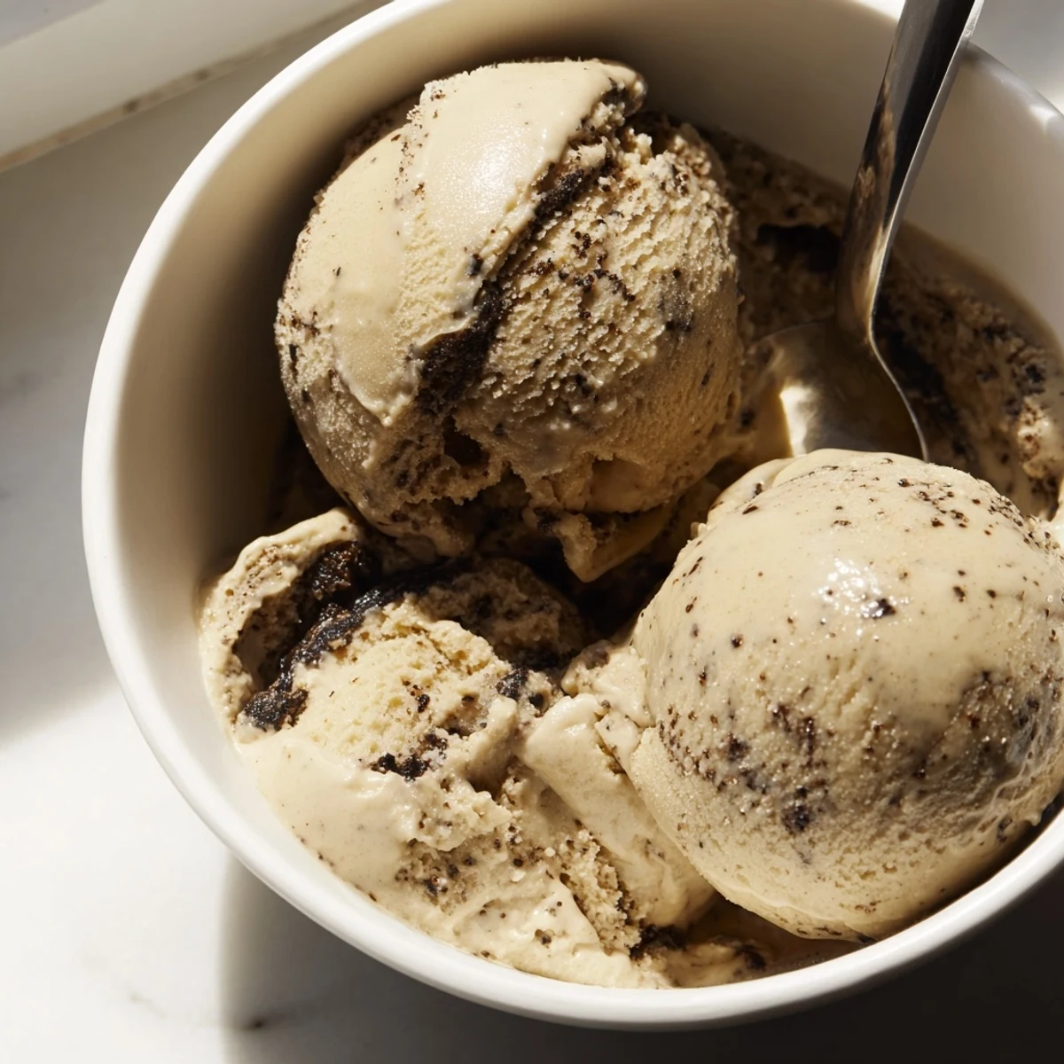 Creamy Vietnamese Coffee Ice Cream scooped into a bowl, topped with crushed ice and a drizzle of sweetened condensed milk.