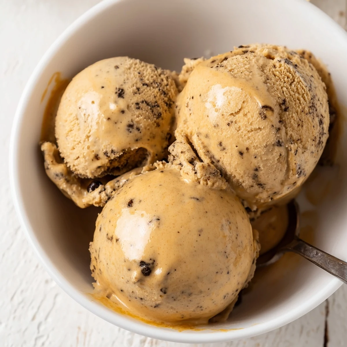 Homemade Vietnamese Coffee Ice Cream in a chilled glass bowl, flecked with coffee grounds and ready to enjoy.