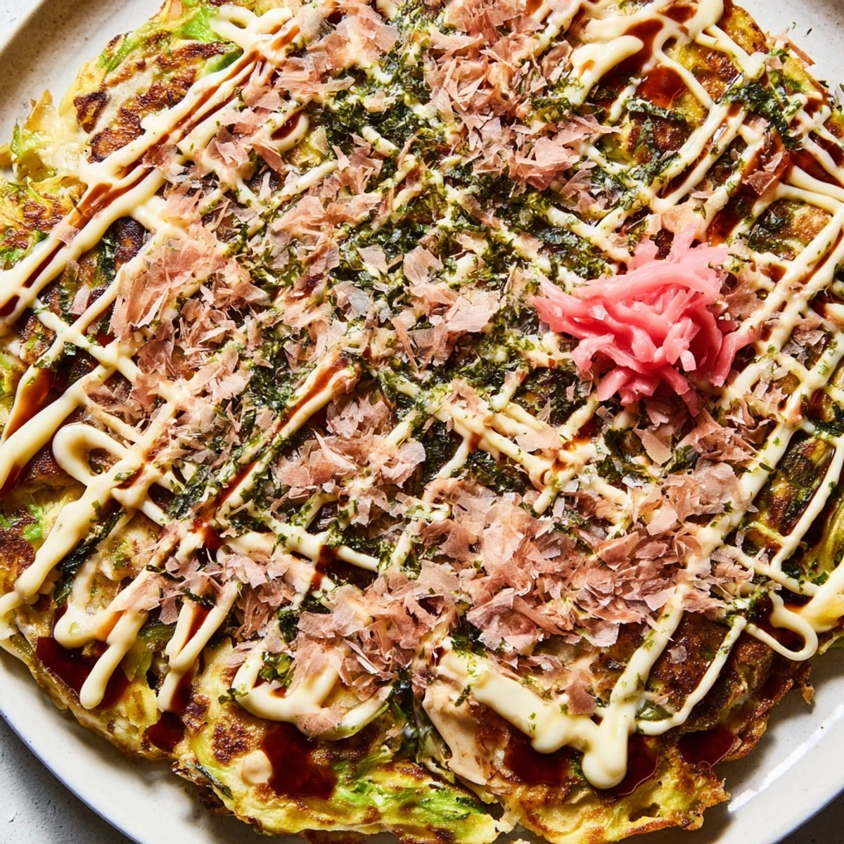 Close-up of a savory Chicken Okonomiyaki plate garnished with pickled ginger and seaweed flakes, ready for a delicious weeknight dinner.