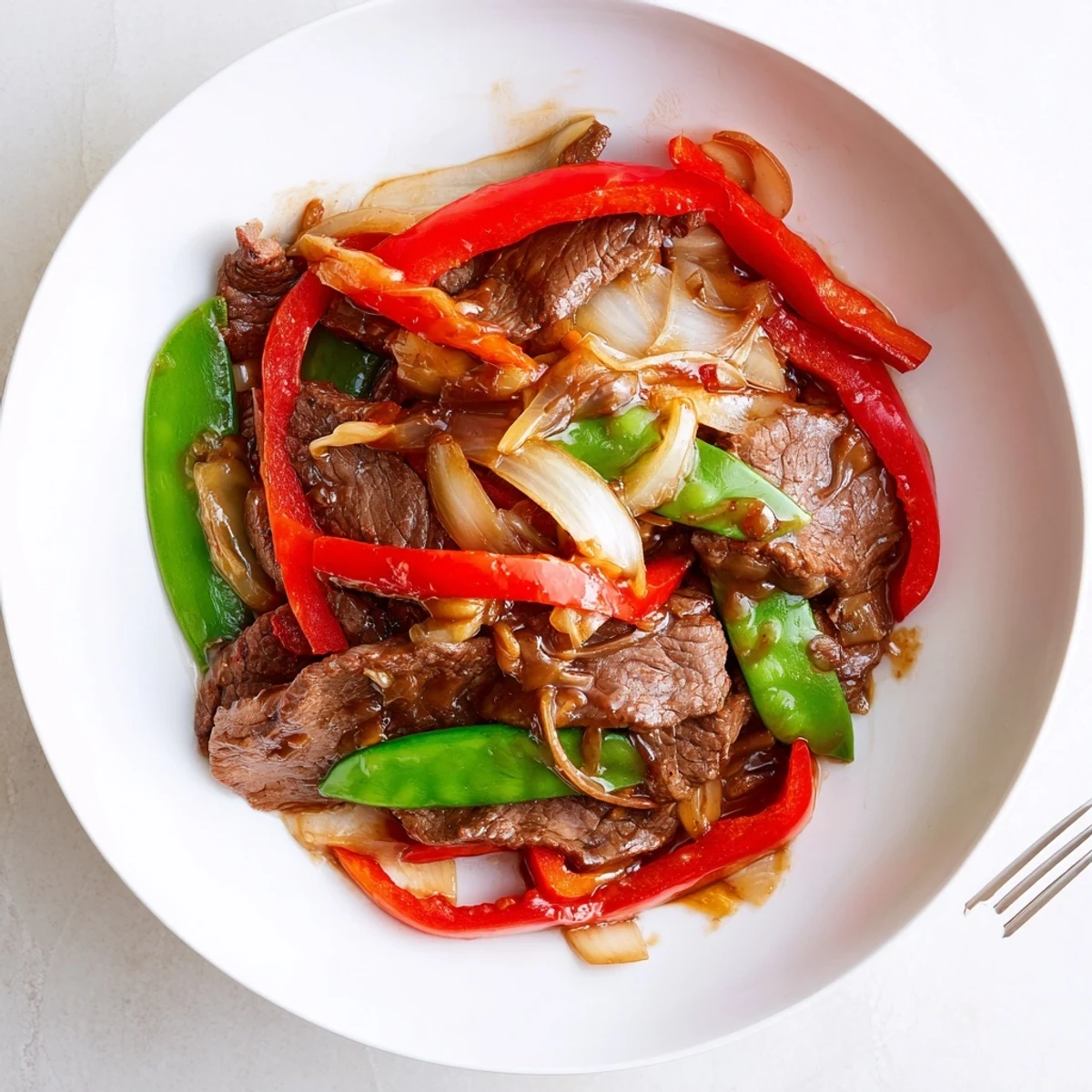 A plate of Beef With Oyster Sauce with fluffy jasmine rice and bright stir-fried snow peas.