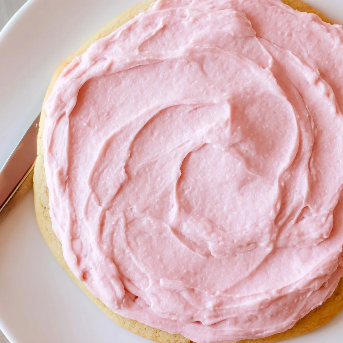Crumbl Sugar Cookies stacked on a plate with pink almond frosting and party ready serving suggestion