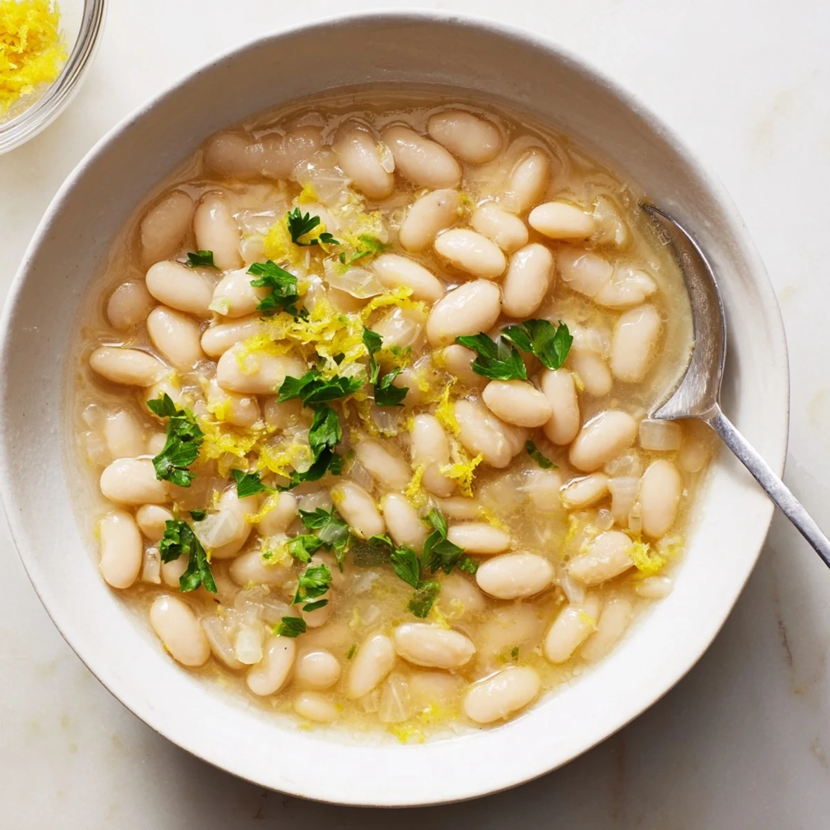 Miso Butter Brothy Beans ladled into a rustic bowl, showcasing tender white beans in a rich, umami-filled broth.