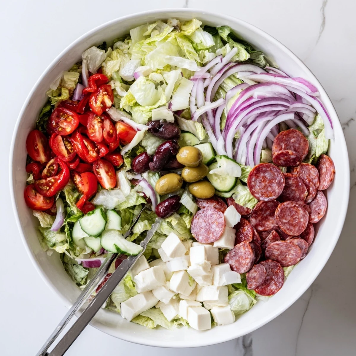 Colorful Italian chopped salad with fresh vegetables, salami, and mozzarella drizzled with zesty homemade dressing.
