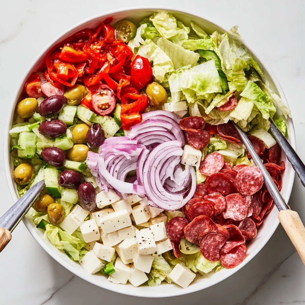Rustic bowl of Italian chopped salad featuring crisp romaine, tomatoes, olives, and cubed cheese in tangy dressing.