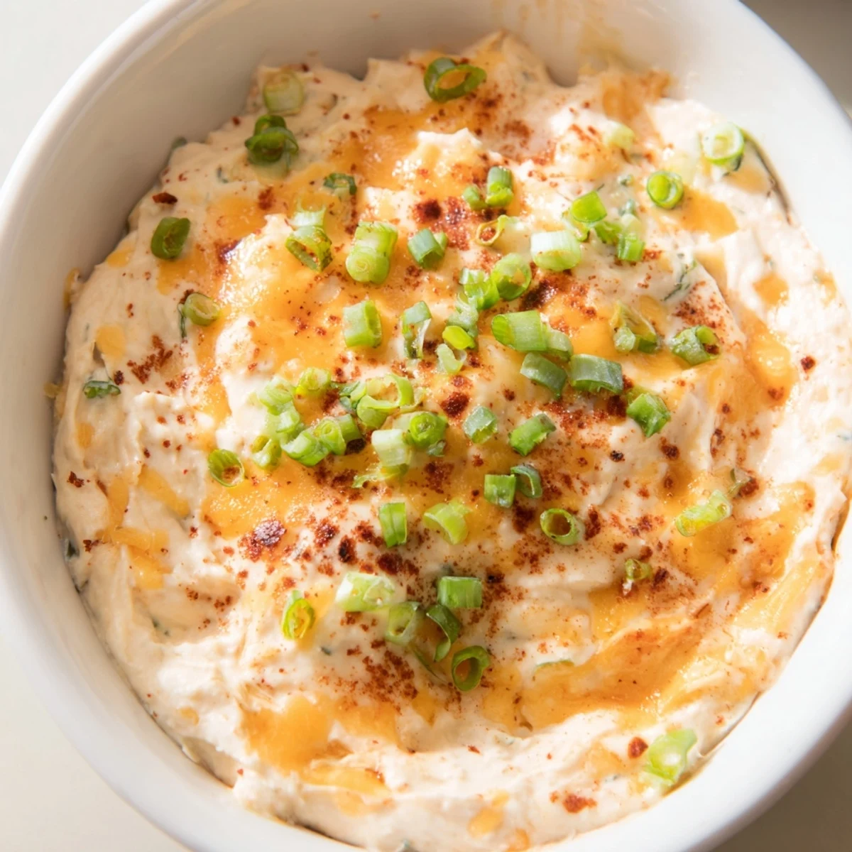 Golden pretzel sticks arranged beside a bowl of tangy savory pretzel dip topped with green onion garnish