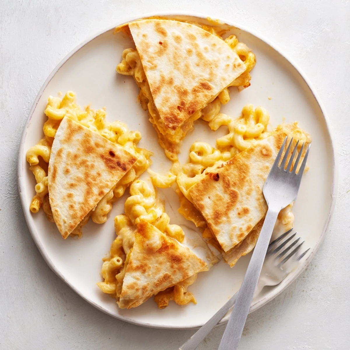 Creamy macaroni and cheese melted inside golden brown tortillas with visible cheese pull
