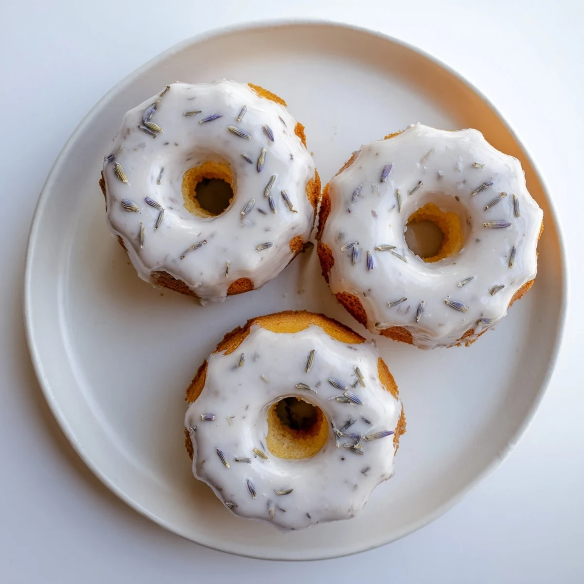 Freshly baked mini lemon cakes topped with floral lavender icing and garnished with lemon zest