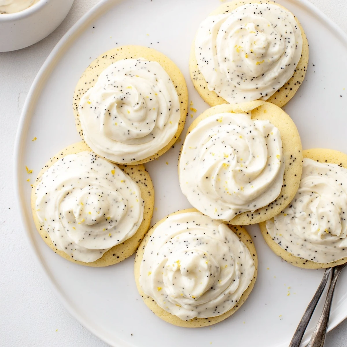 Golden lemon poppy seed cookies with cheesecake frosting piped high on a cooling rack