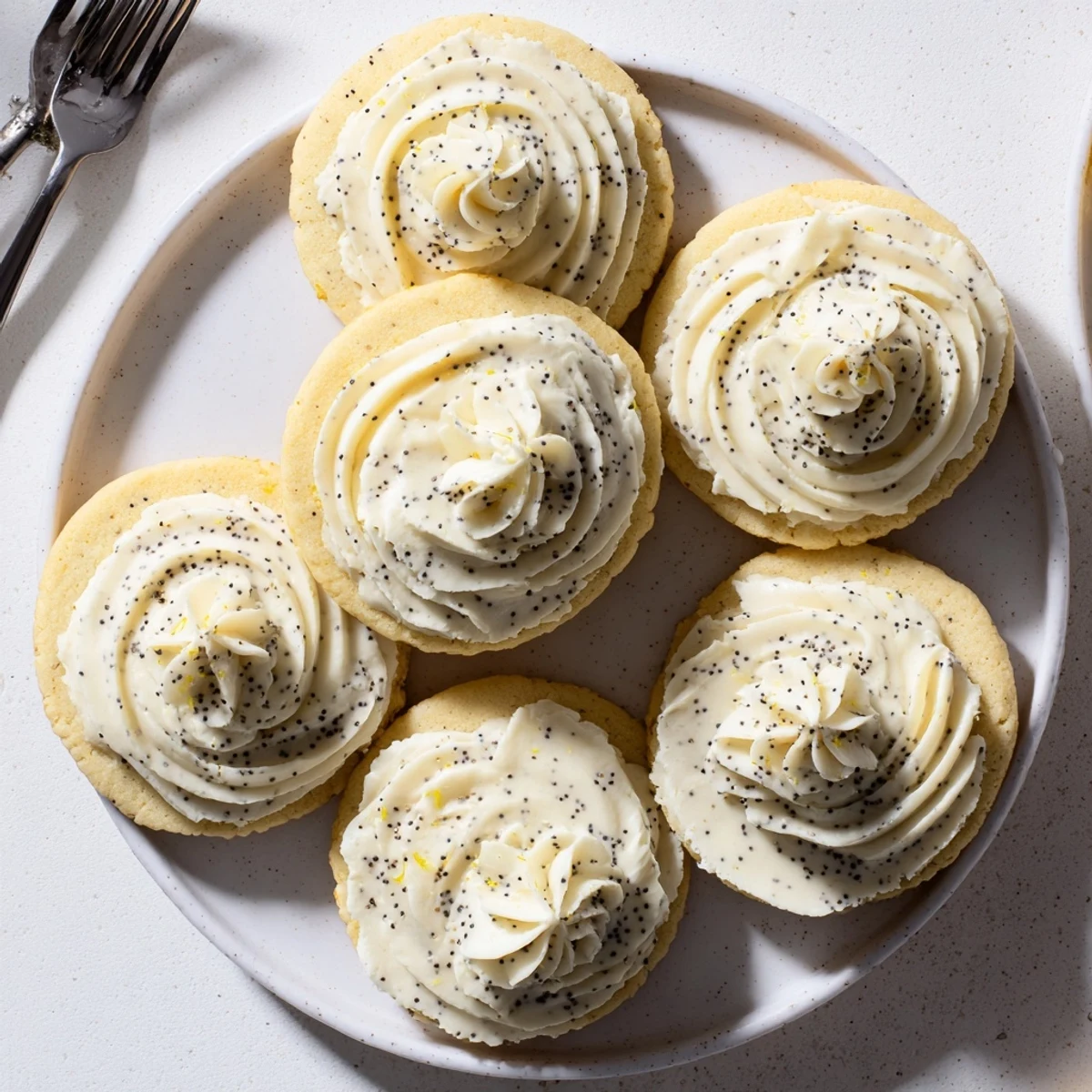 Soft lemon poppy seed cookies with tangy cheesecake frosting garnished with fresh lemon zest