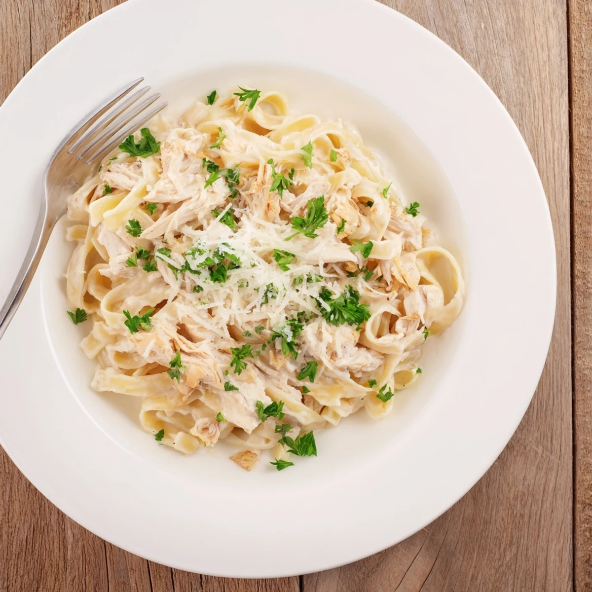 Slow cooker Chicken Alfredo pasta dish garnished with fresh parsley and served piping hot for a comforting weeknight dinner
