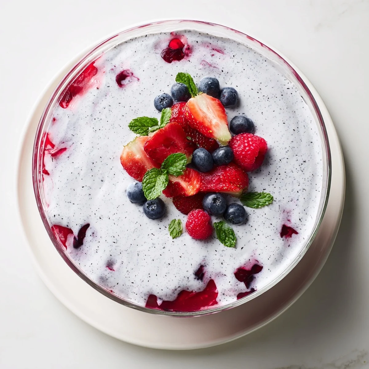 Summer vanilla mousse berry jello dessert served in individual glasses with whipped vanilla layer over jewel-toned berry gelatin
