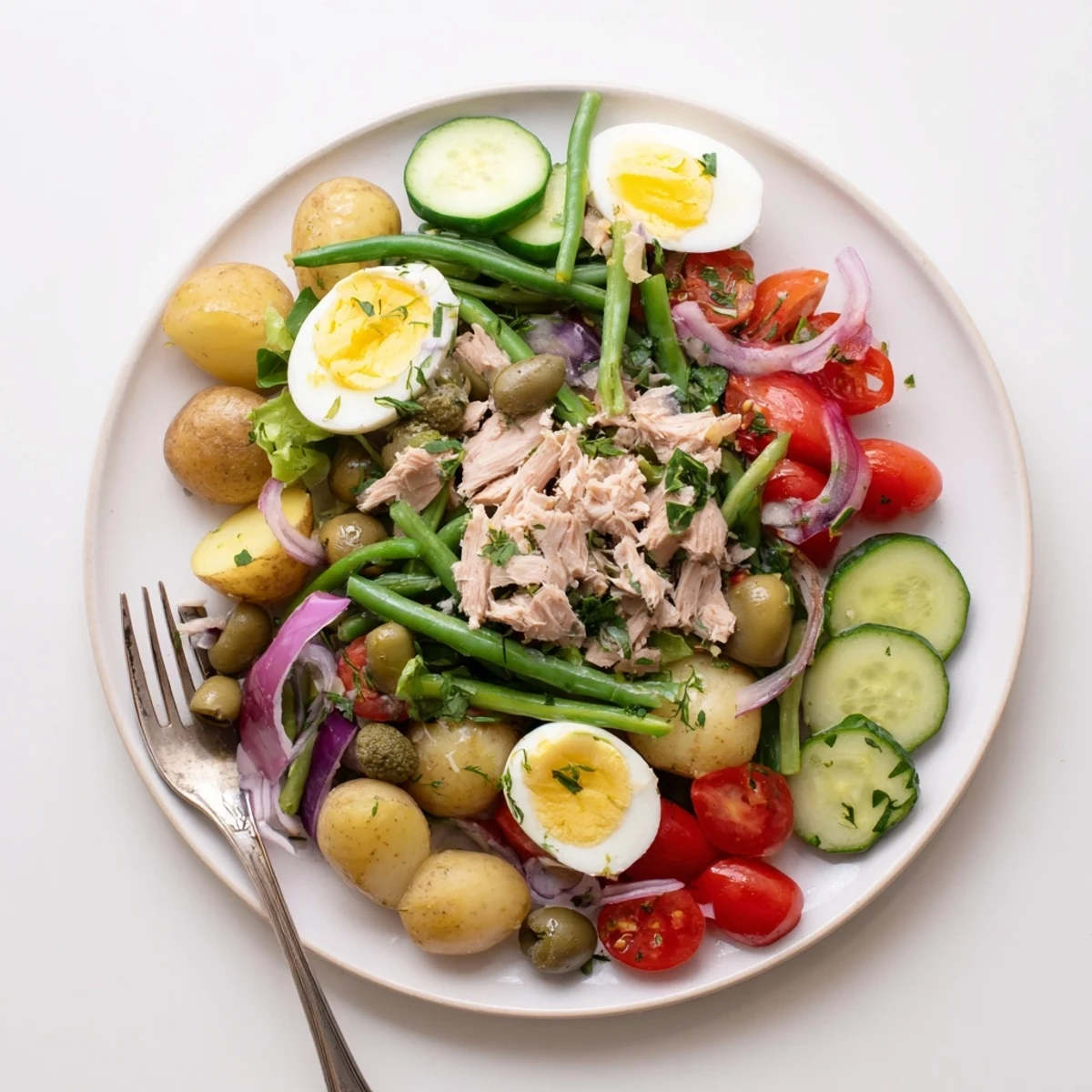 Fresh Classic Niçoise Salad featuring crisp vegetables, flaky tuna, briny olives, and hard-boiled eggs drizzled with tangy vinaigrette