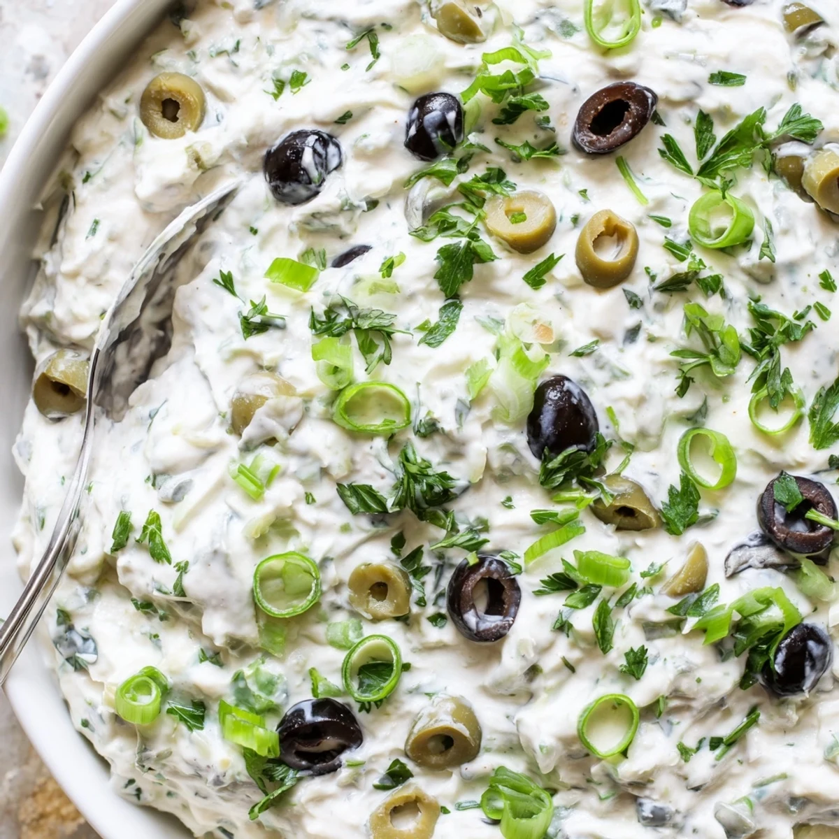 Creamy white olive dip garnished with green onions and paired with crispy pita chips