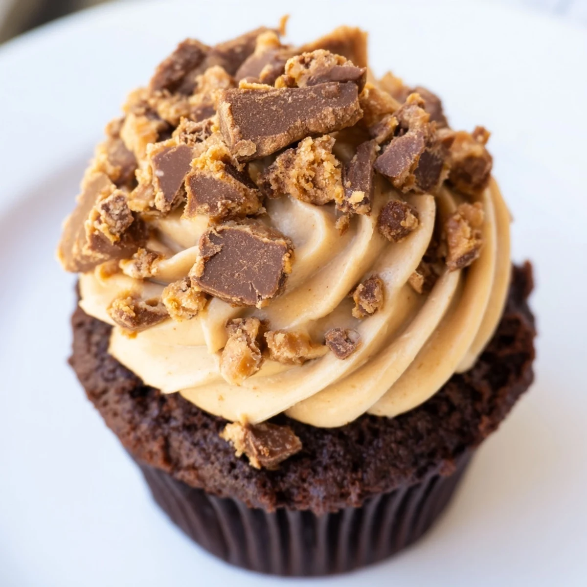 Decadent Butterfinger Cupcakes featuring filled centers and creamy peanut butter frosting garnished with Butterfinger crumbles
