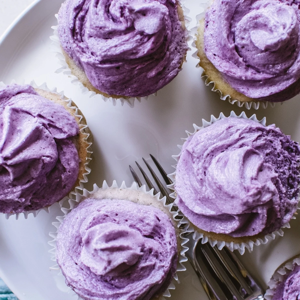 Purple frosted grape soda cupcakes topped with swirling grape buttercream on a white plate