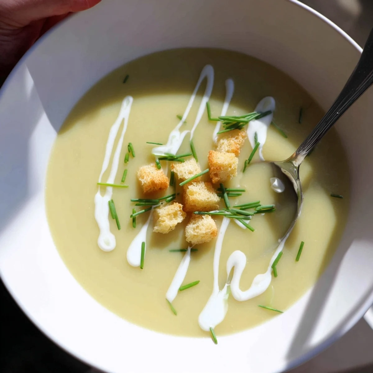 Creamy potato leek soup garnished with fresh chives in a white bowl
