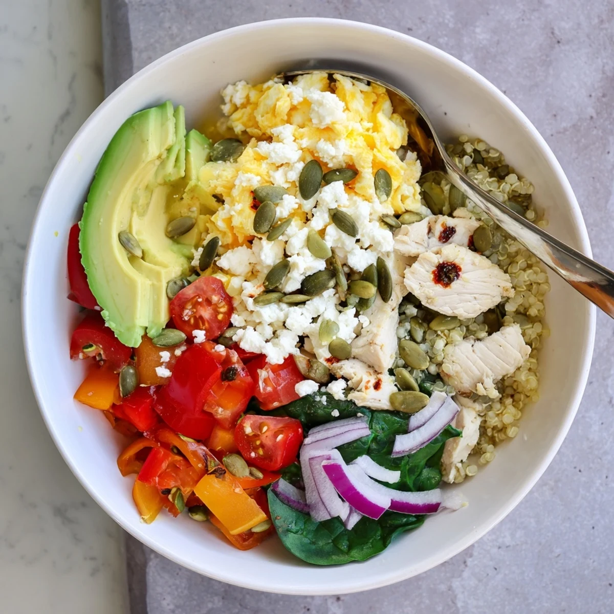 Colorful easy high protein breakfast bowl loaded with scrambled eggs, fresh vegetables, and sliced avocado