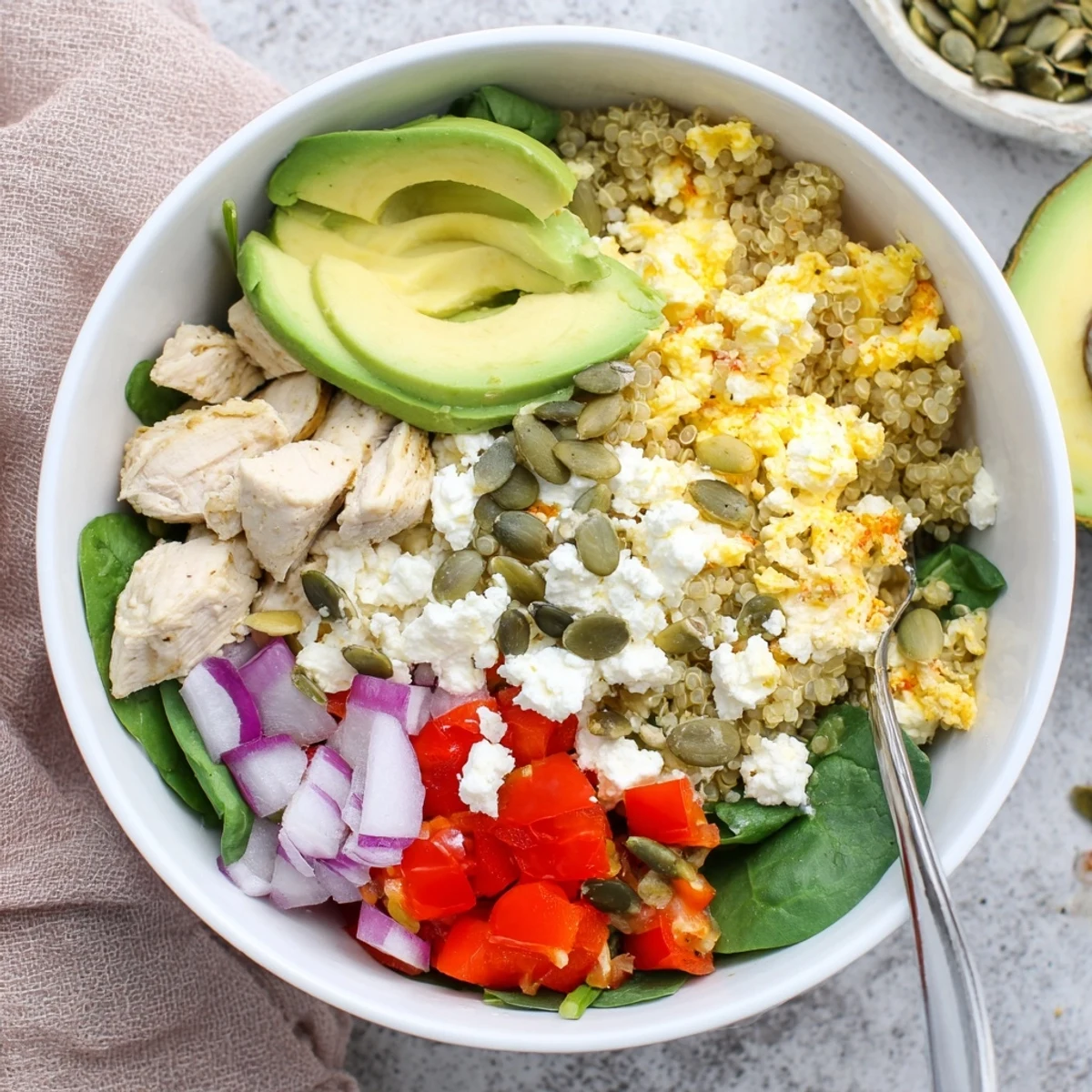 Savory easy high protein breakfast bowl packed with fluffy scrambled eggs, quinoa, diced chicken, feta