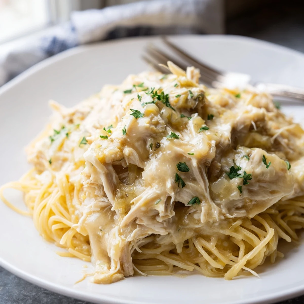 Golden Crock Pot Angel Chicken breasts in savory Italian sauce atop fluffy angel hair pasta