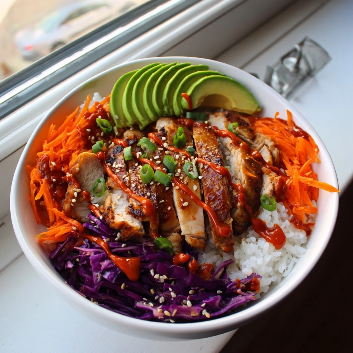 Vibrant bowl featuring sweet and savory Korean BBQ chicken thighs atop rice with fresh cucumber, carrots, and spicy mayo