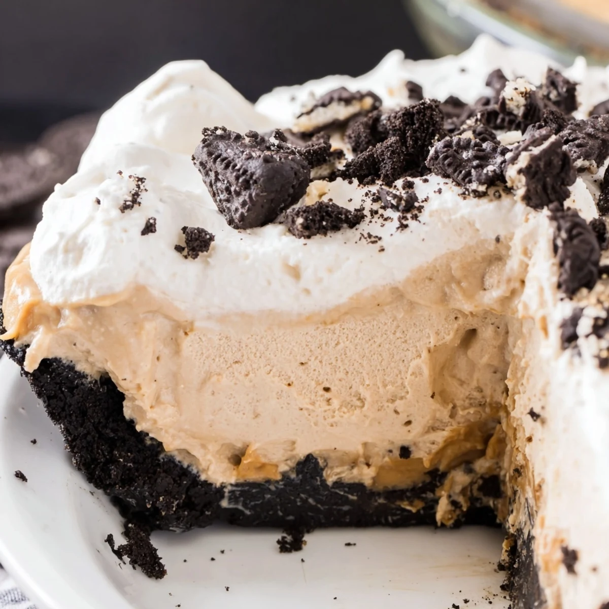 Creamy peanut butter Oreo pie with whipped topping and cookie crumbles on a dessert plate